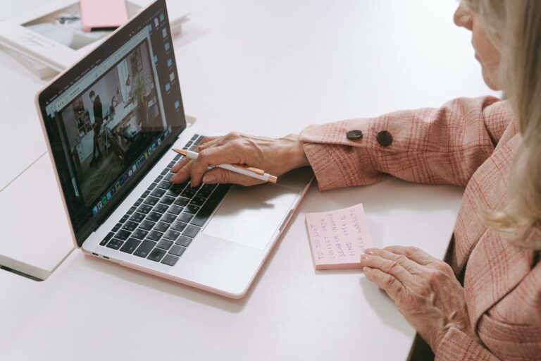 Senior woman using a laptop with sticky notes for planning and organizing tasks.